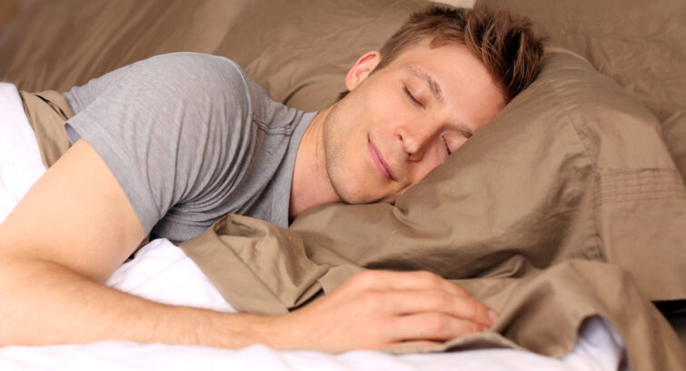 Young man comfortably sleeping in his bed